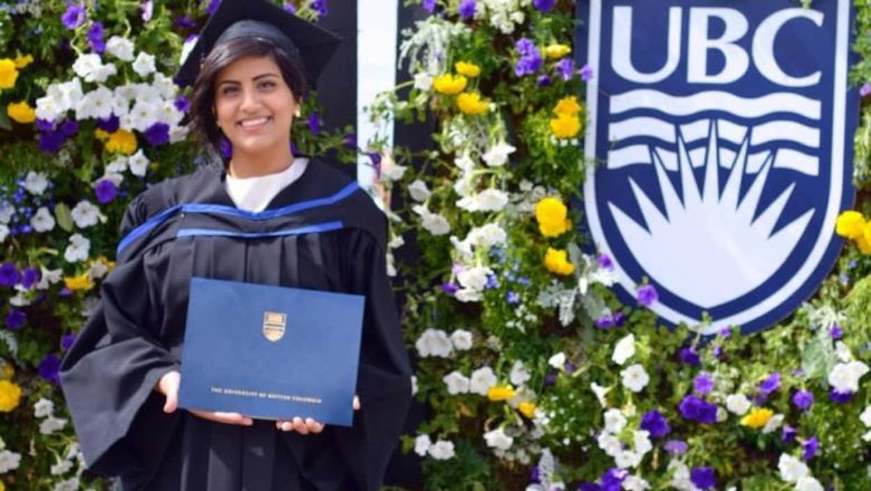 Une jeune diplômé devant des fleurs.