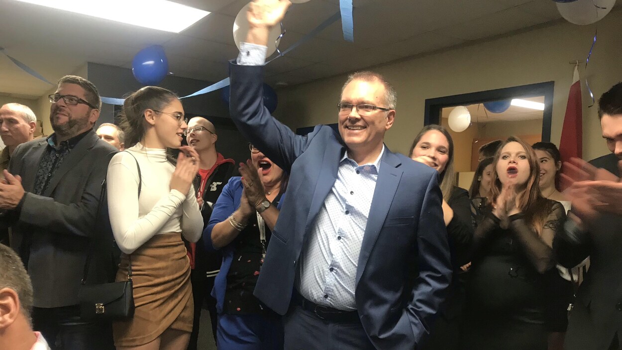 Luc Berthold levant son bras en signe de victoire, entouré de militants