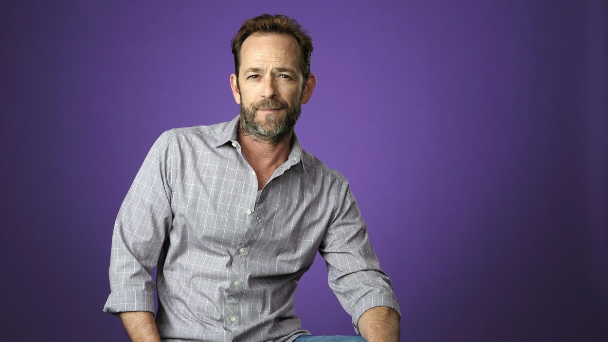 Portrait de Luke Perry sur un fond violet.