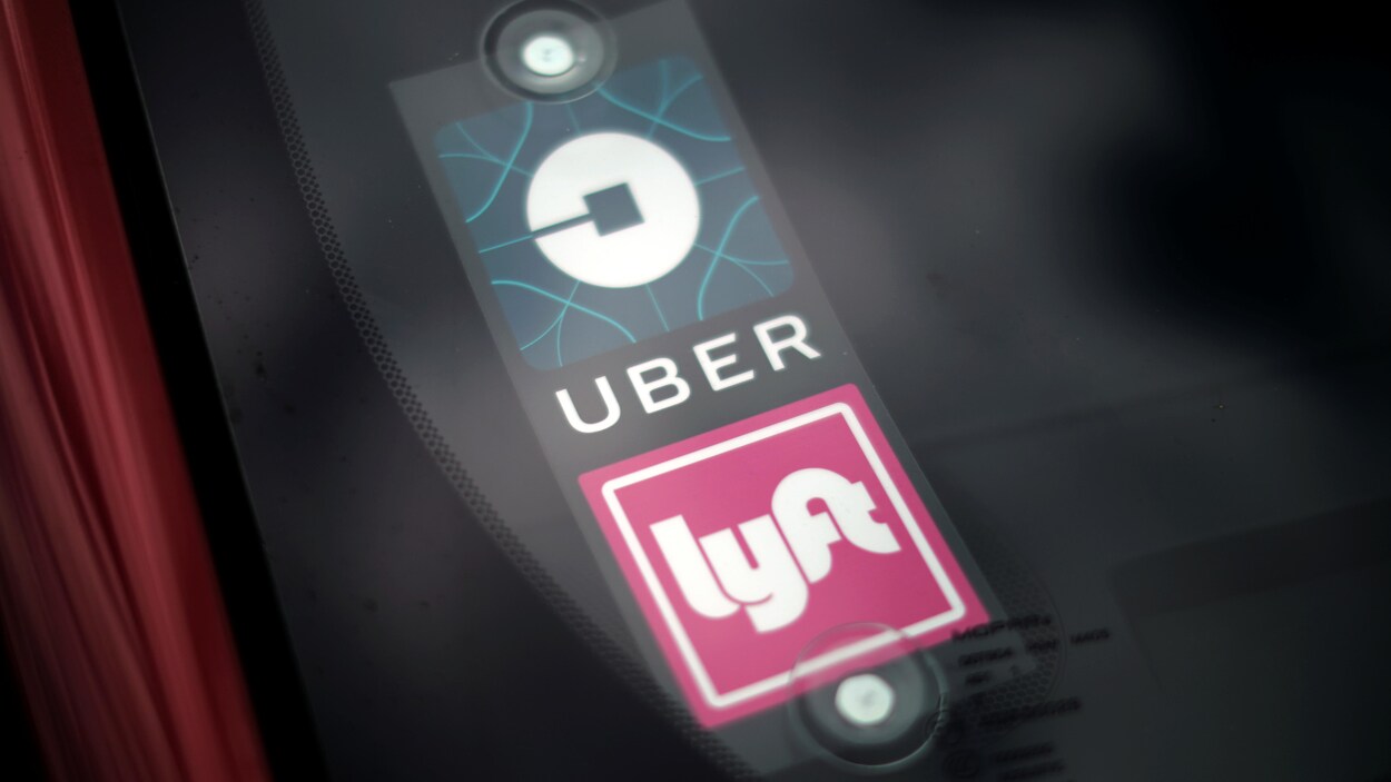 Logos d'Uber et Lyft affichés dans la fenêtre arrière d'un véhicule routier.