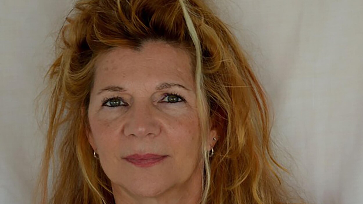 Elle sourit à la caméra.