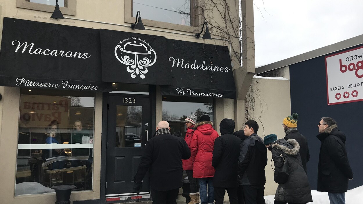 Une file de clients devant une pâtisserie en hiver.
