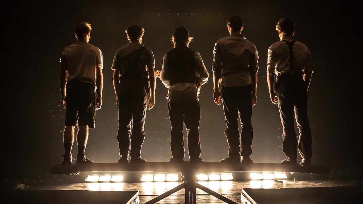 Des membres de la troupe Machine de cirque, de dos, lors d'un spectacle.