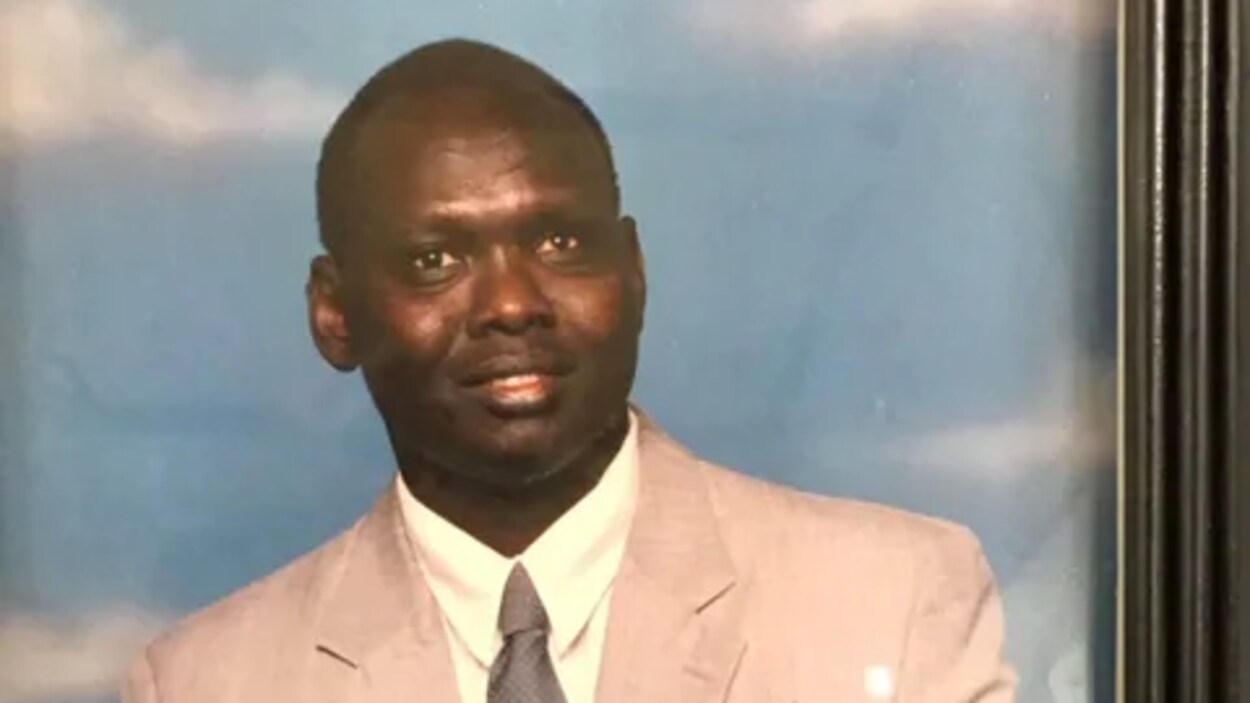 Un homme souriant légèrement.