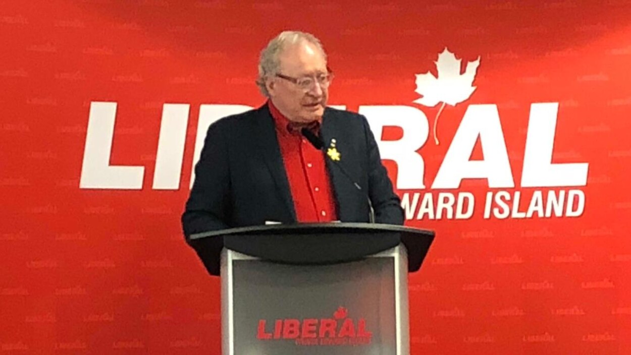 Wade MacLauchlan sur une scène devant une grande affiche du Parti libéral