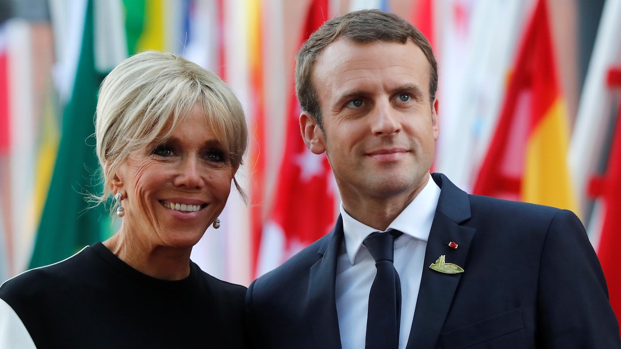 Le président français, Emmanuel Macron, et son épouse, Brigitte, posent pour les photographes devant des drapeaux.