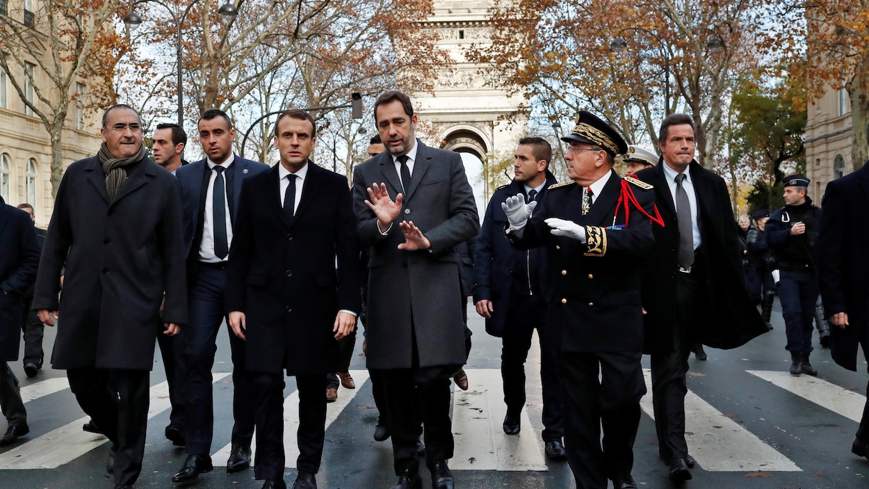 Emmanuel Macron marche dans les rues de Paris avec Christophe Castaner, le ministre de l'Intérieur et des gardes du corps. Il y a aussi un haut gradé.