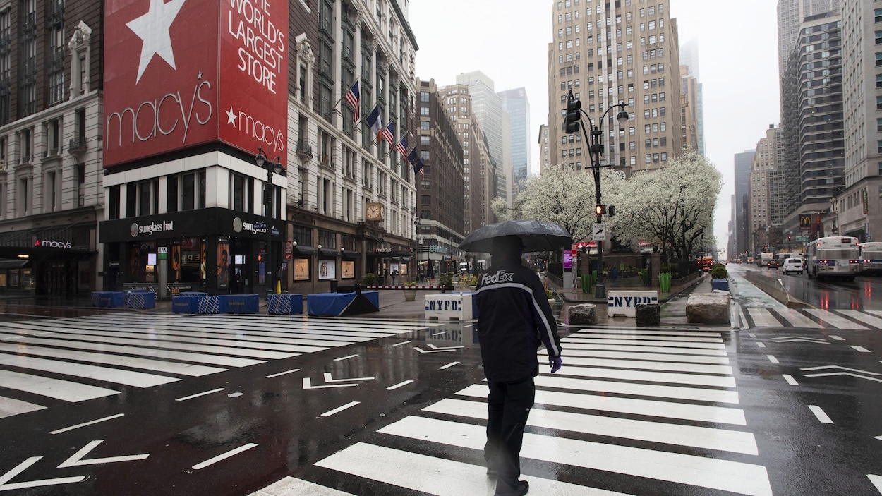 Un homme traverse une rue près du Macy's de New York.