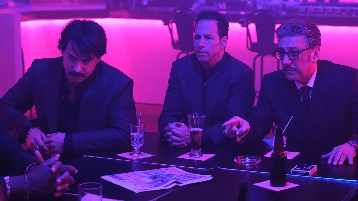 Trois hommes en costume sont dans un bar de nuit.