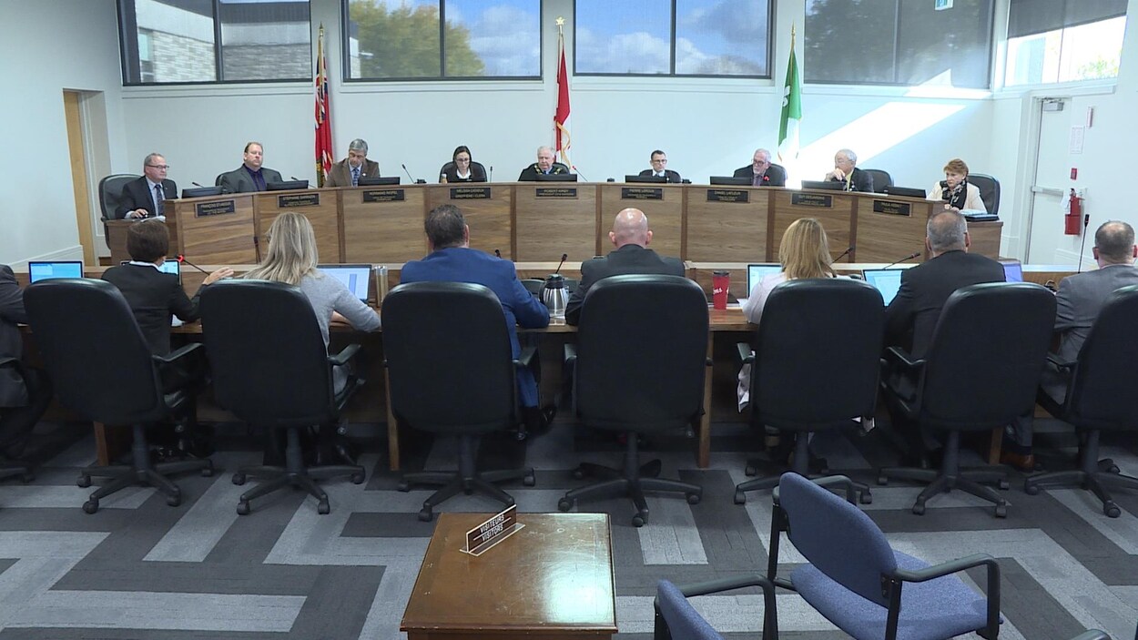 Des élus autour d'une table dans une grande salle de réunion.