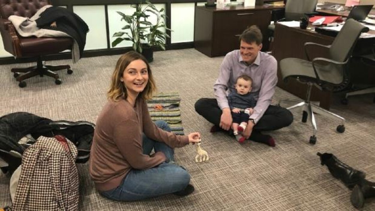 Mairin Loewen est assise par terre. Le maire de Saskatoon assis par terre en face d'elle avec le fils de cette dernière assis sur ses genoux. Mairin Loewen est assise par terre. Le maire de Saskatoon assis par terre en face d'elle avec le fils de cette dernière assis sur ses genoux.