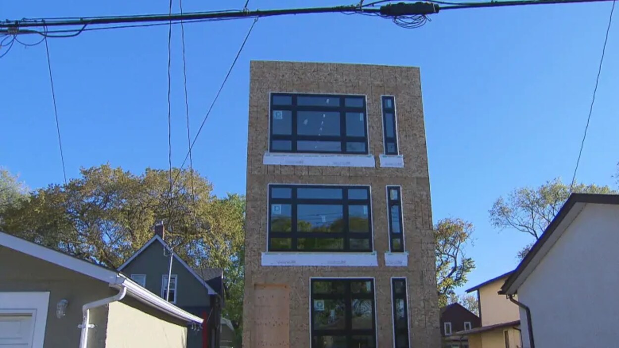Un bâtiment de trois étages est entouré de maisons dans un quartier résidentiel.