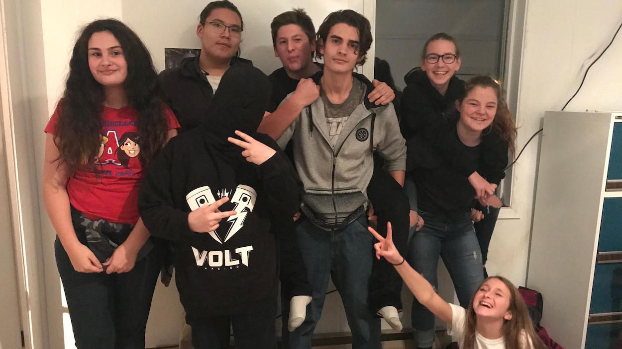 Des adolescents posent pour la caméra, certains riant, d'autres faisant des signes de paix.