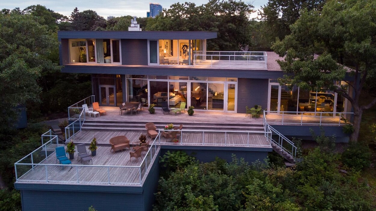 Photo d'une maison contemporaine à deux étages, beaucoup de fenêtres et une grande aire de vie à l'extérieur.