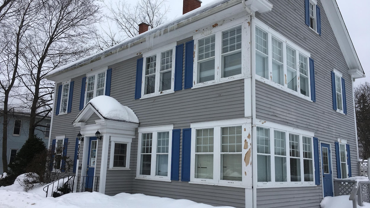 Une maison grise de deux étages avec de multiple fenêtres et à la peinture décrépite Une maison grise de deux étages avec de multiple fenêtres et à la peinture décrépite