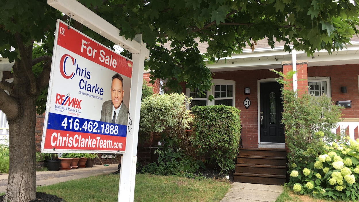 Une affiche de maison à vendre devant une demeure.