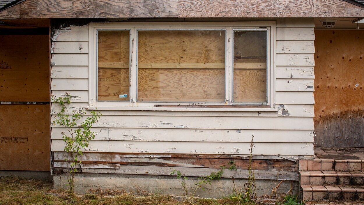 Plan serré d'une fenêtre d'une maison condamnée par des panneaux de bois.