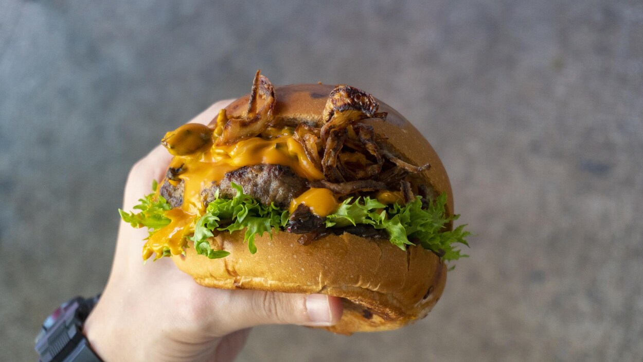 Un hamburger dans une main.