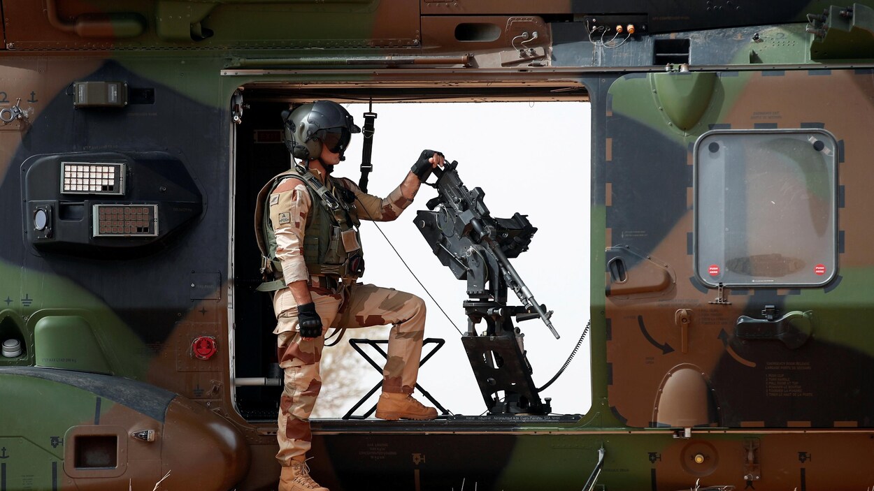 Dans un hélicoptère au sol, un soldat français se tient à côté d'une arme automatique. Dans un hélicoptère au sol, un soldat français se tient à côté d'une arme automatique.