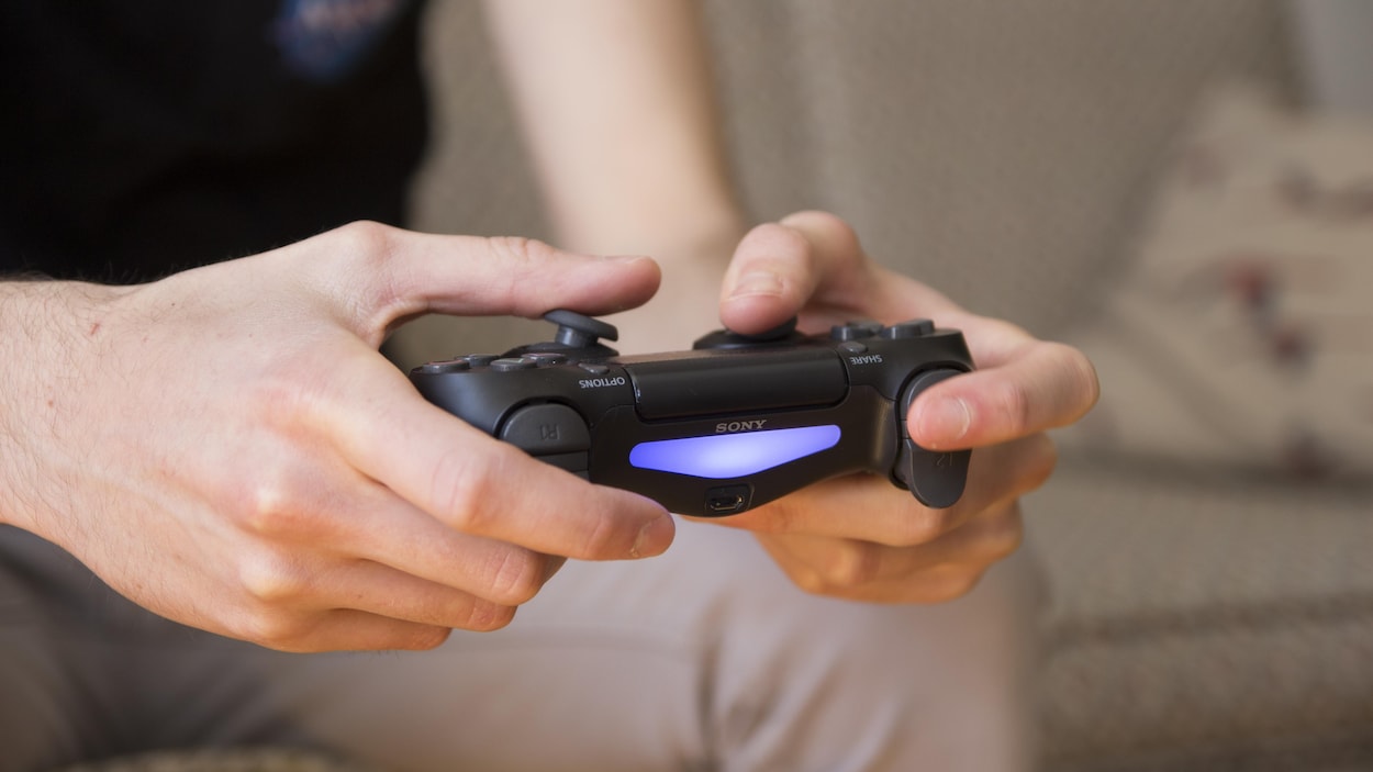 Un joueur tient une manette Un joueur tient une manette