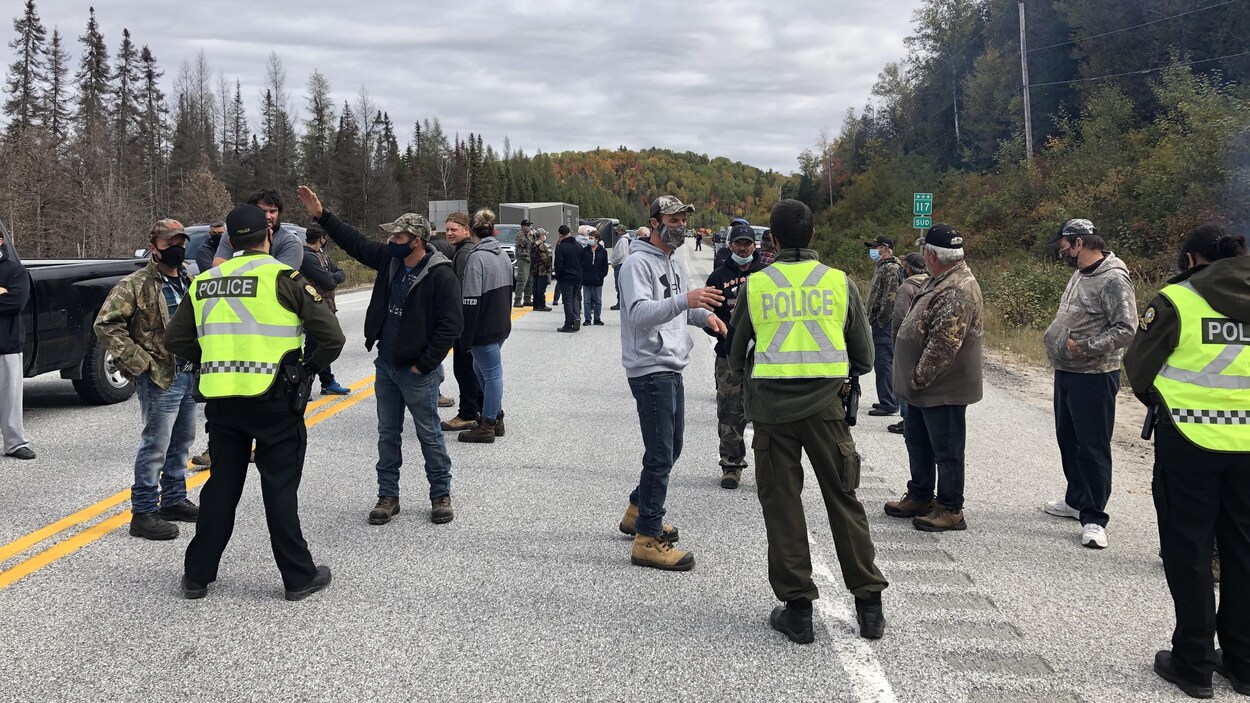 Des policiers et des chasseurs discutent sur la chaussée de la route 117, dans la réserve faunique La Vérendrye.