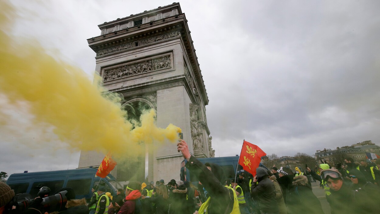 Un manifestant tient un nuage de fumée lors d'un rassemblement des gilets jaunes sur les Champs-Élysées, à Paris, le 16 mars 2019.