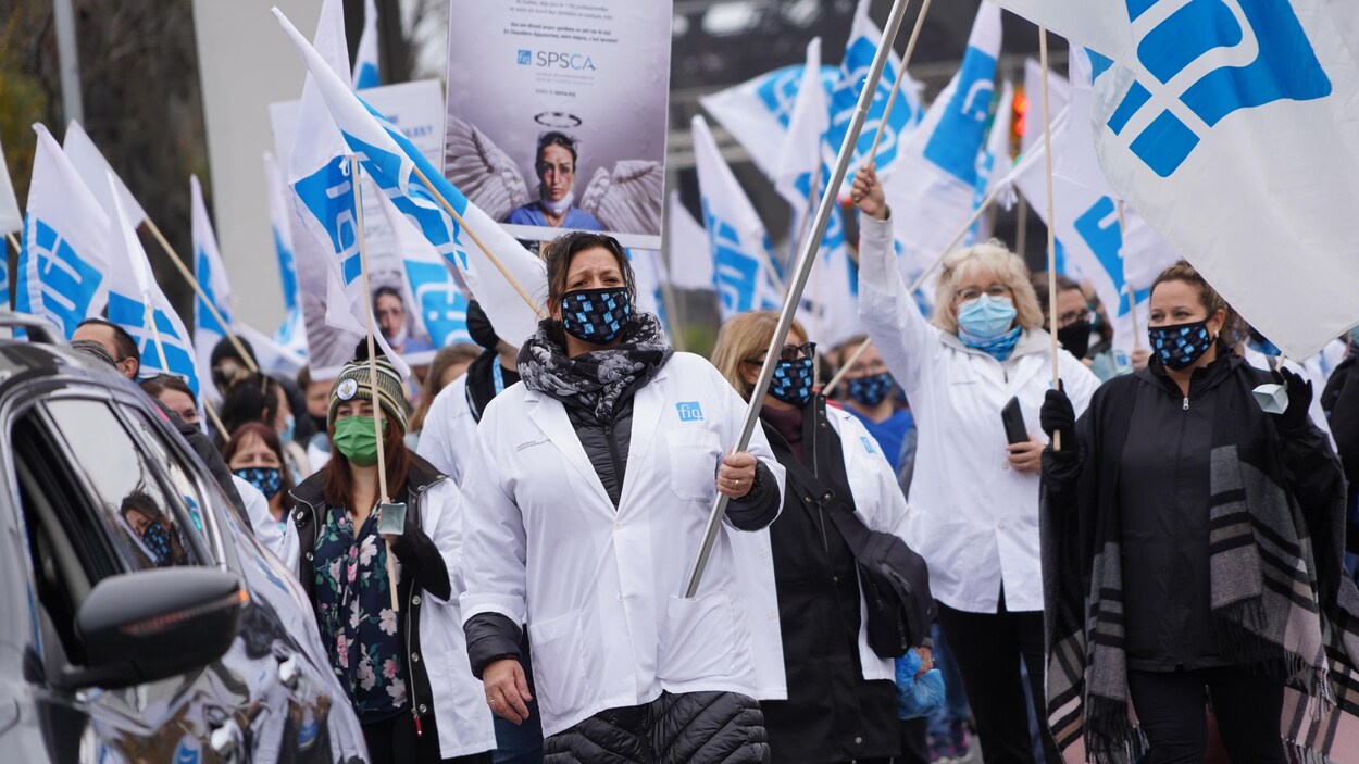 Des infirmières défilent dans la rue en brandissant des drapeaux.