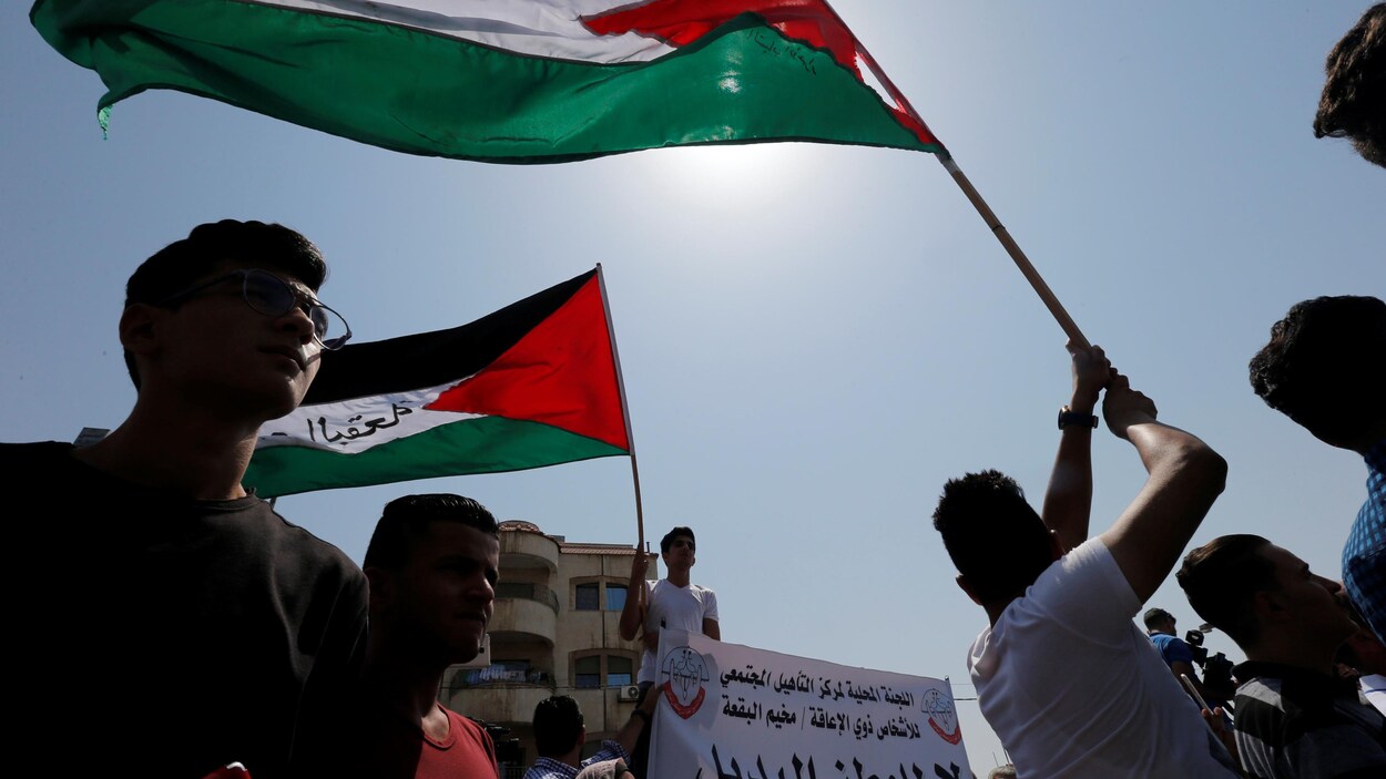 Des réfugiés palestiniens brandissent le drapeau palestinien lors d'une manifestation dans la capitale jordanienne, Amman.