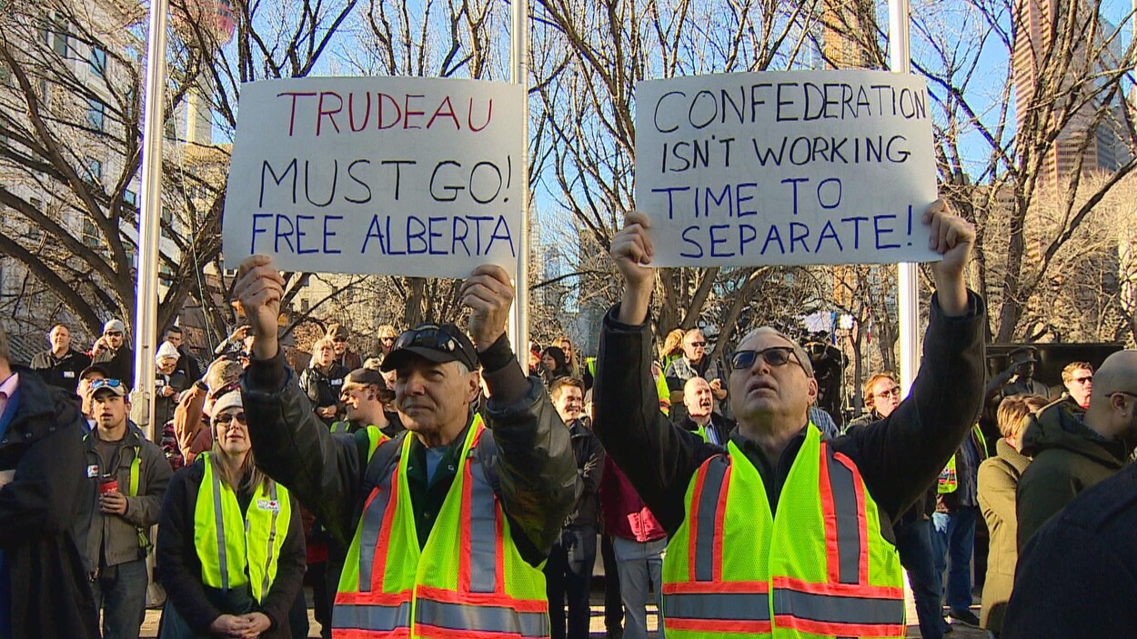 Deux manifestants à un ralliement en faveur de l'énergie pétrolière portent des pancartes en faveur de l'indépendance de l'Alberta.