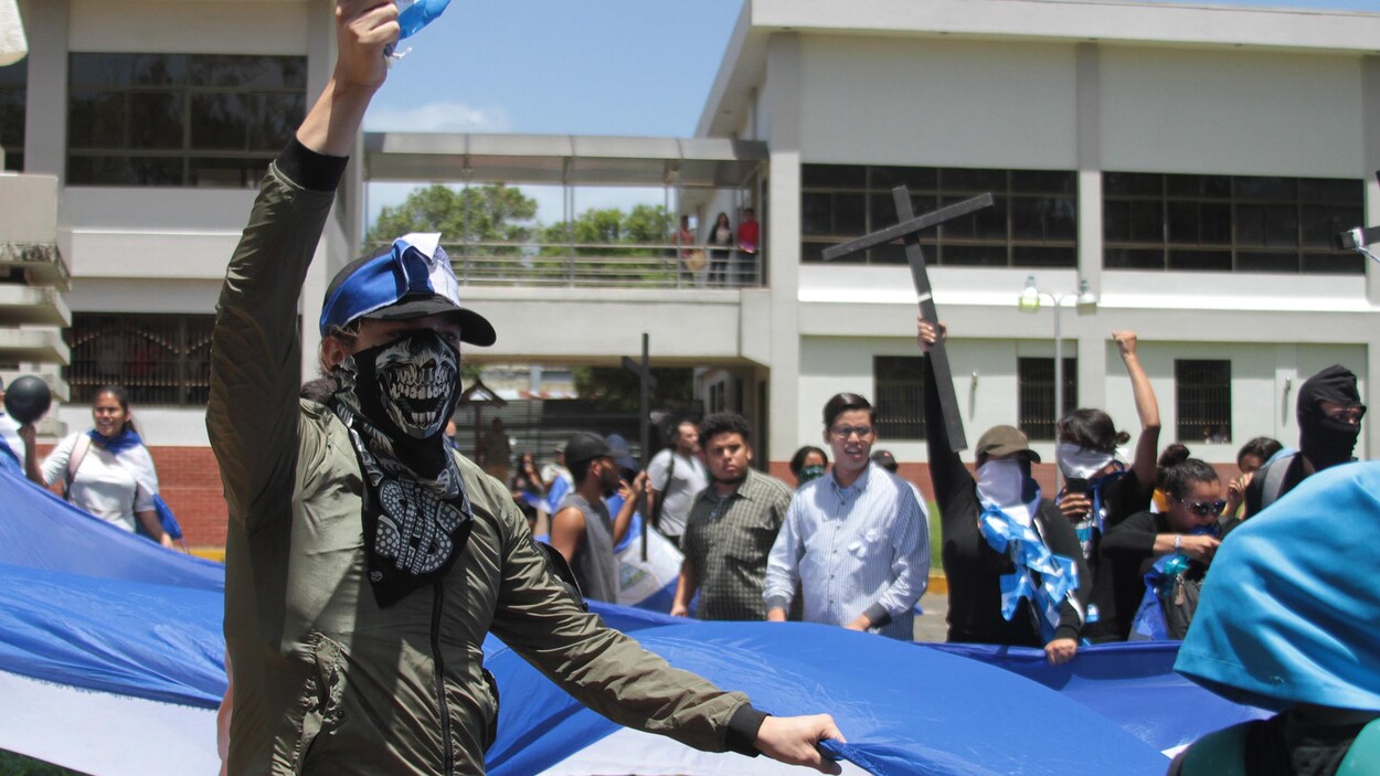 Un homme masqué lève le poing lors d'une manifestation au Nicaragua.