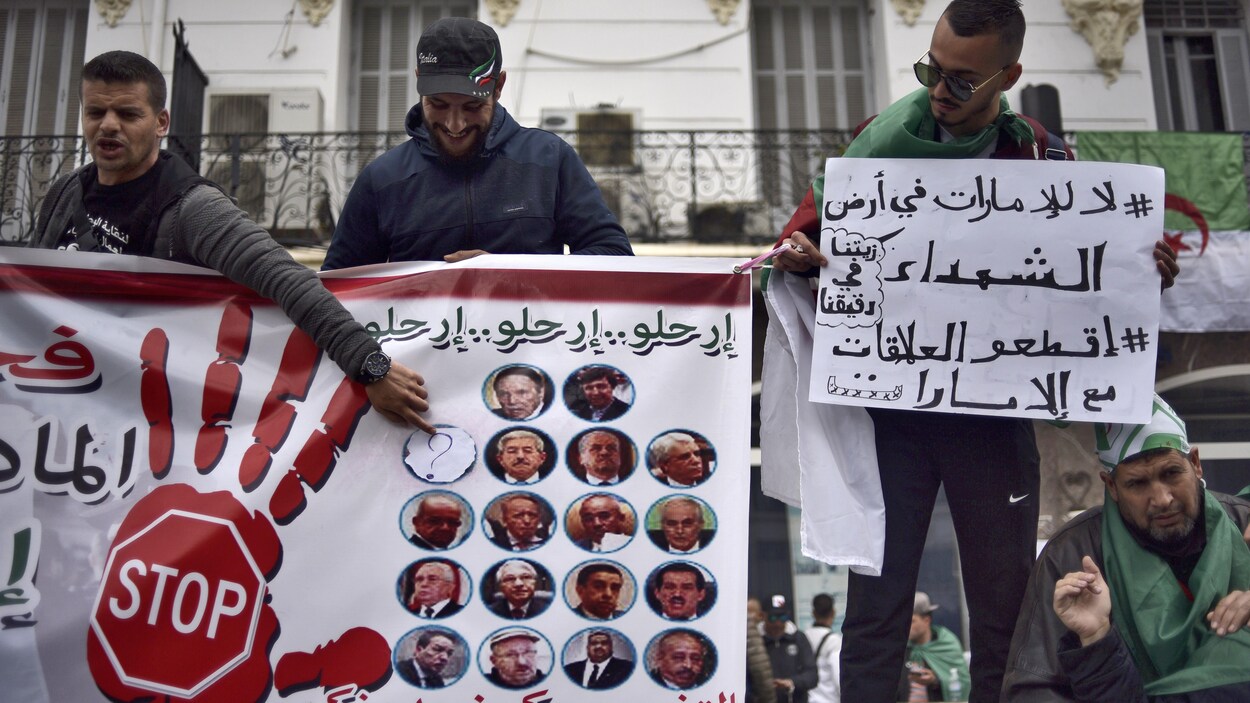 Des manifestants algériens avec des pancartes.