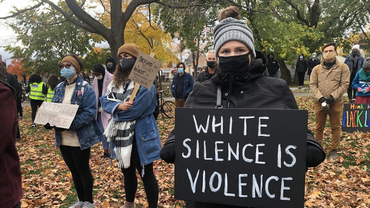 Des manifestants tiennent des pancartes sur lesquelles on peut lire les slogans : «le silence des Blancs est une forme de violence» et «pas de justice, pas de paix».