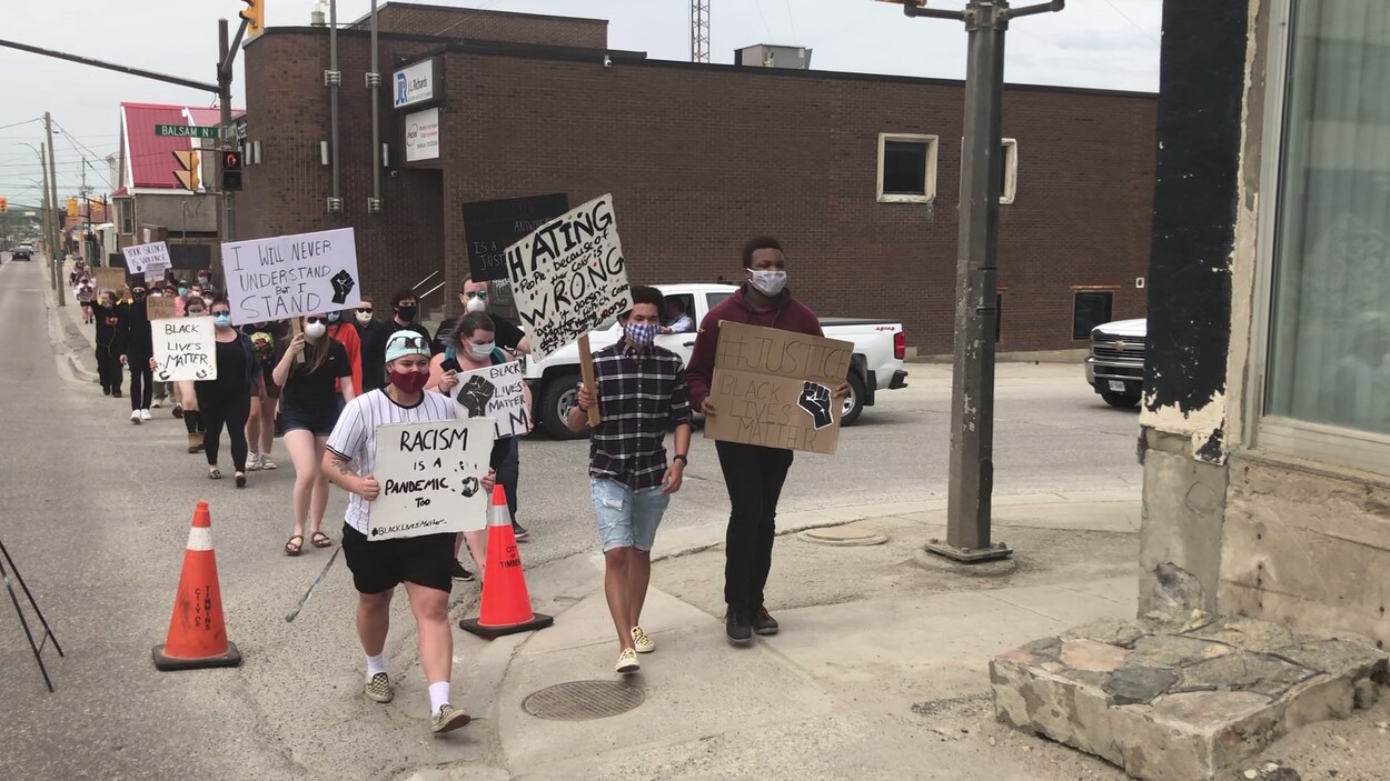 Des manifestants marchent sur un trottoir.