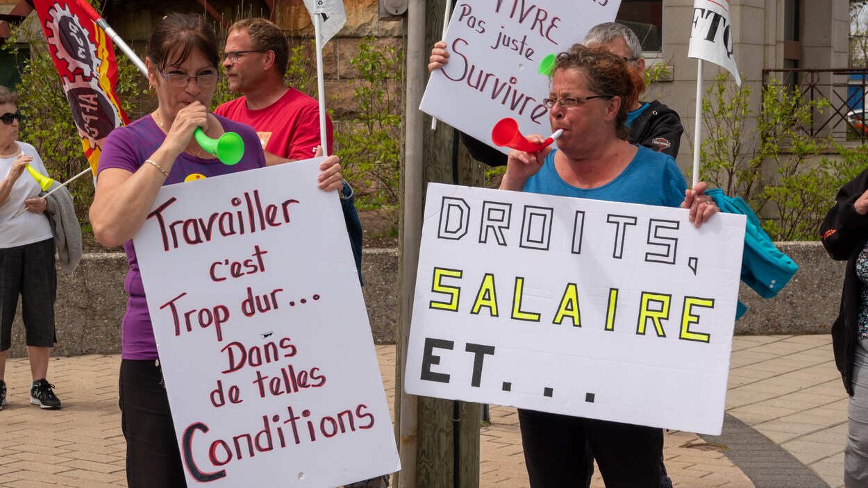 Deux femmes avec des pancartes en avant plan d'une manifestation