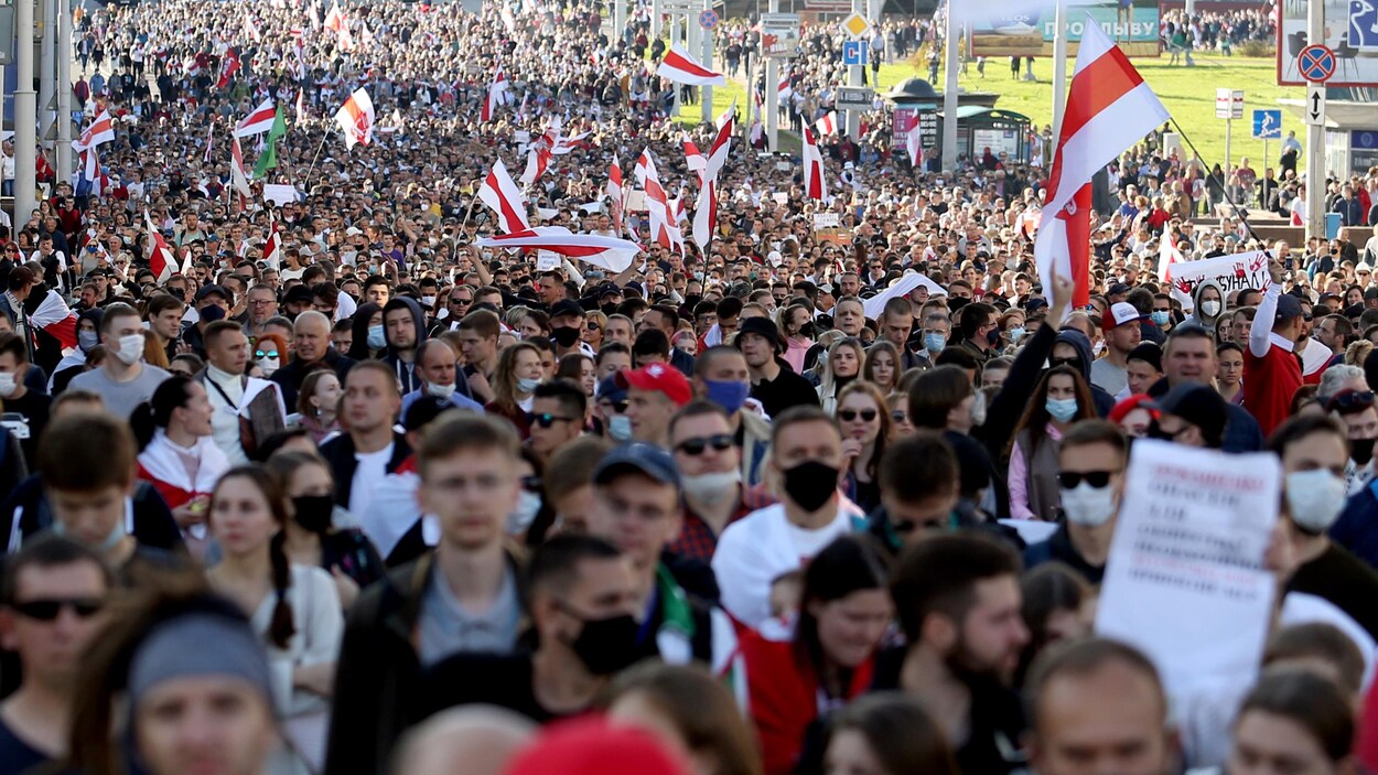 Une foule immense marche avec des drapeaux.