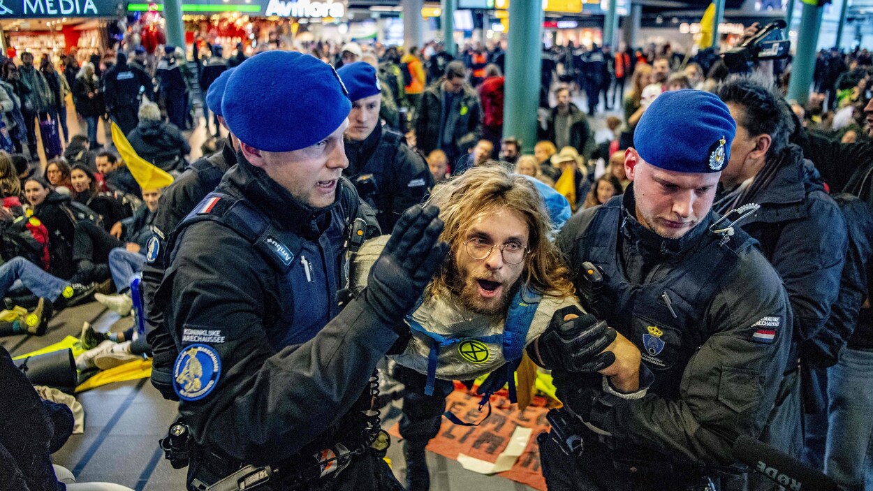 Des policiers néerlandais traînent un activiste du climat qui porte un logo du groupe Extinction Rebellion.