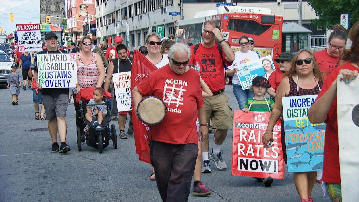 Des gens marchent dans les rues d'Ottawa avec des pancartes.