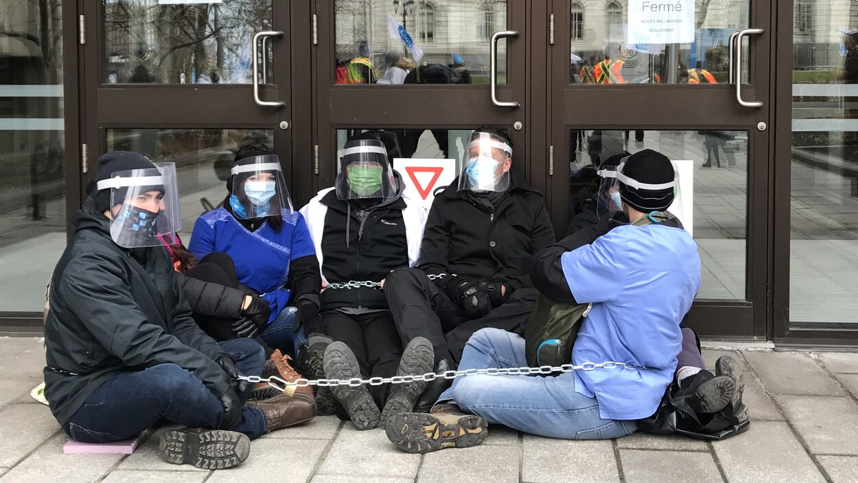 Des travailleuses de la santé se sont enchaînées devant des portes autour de l'édifice du Conseil du Trésor.