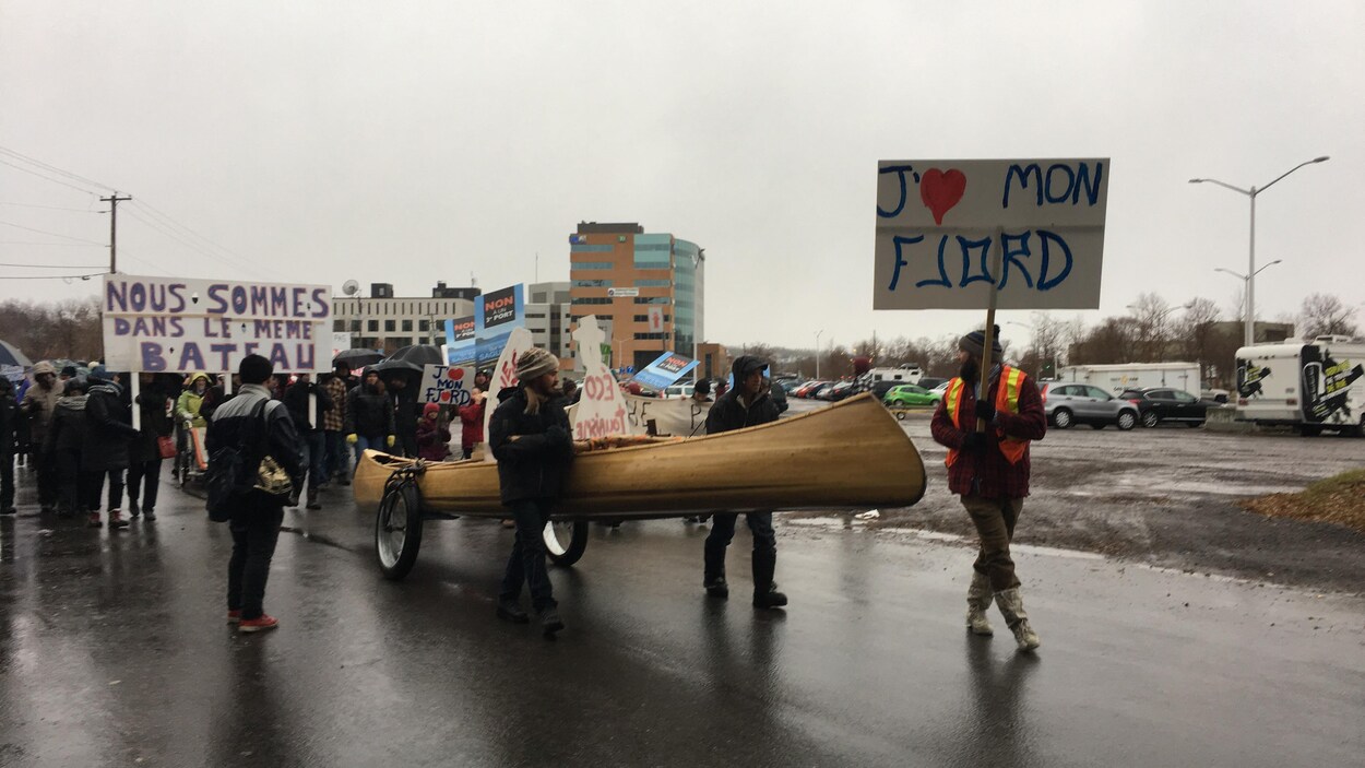Des gens qui manifestent dans la rue avec un canot.