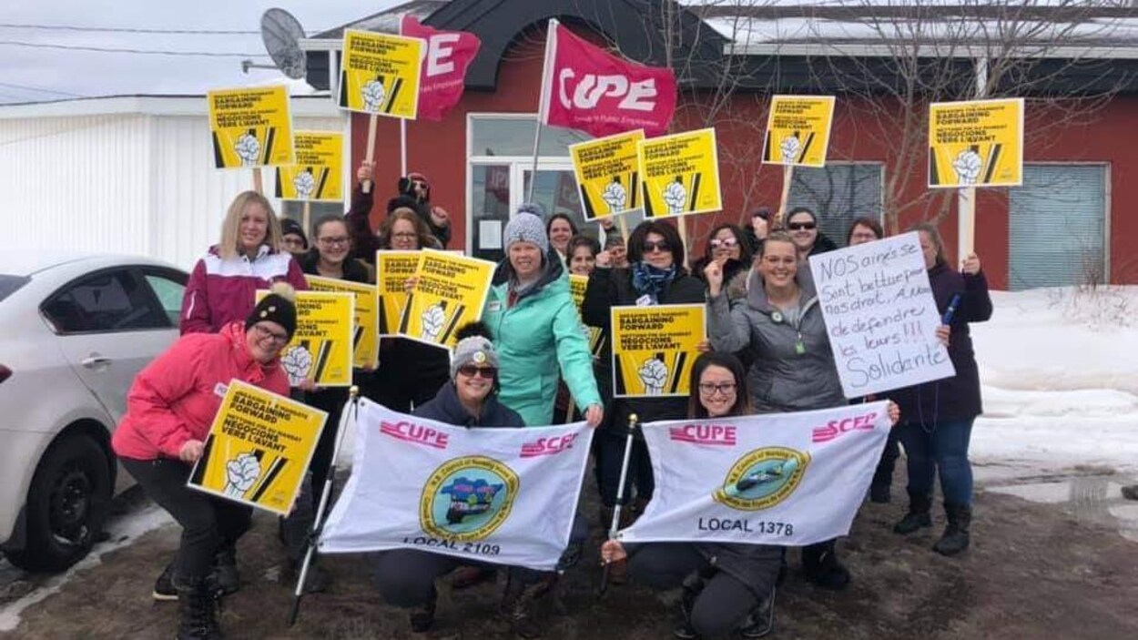 Une vingtaine de manifestants posent pour une photo, pancartes à la main.