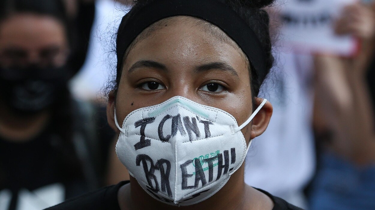 Une jeune femme noire portant un masque.