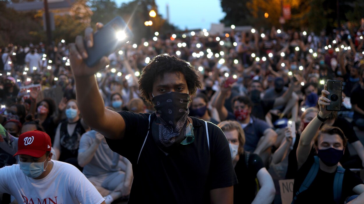 Des manifestants brandissent leur téléphone intelligent lors d'une marche.