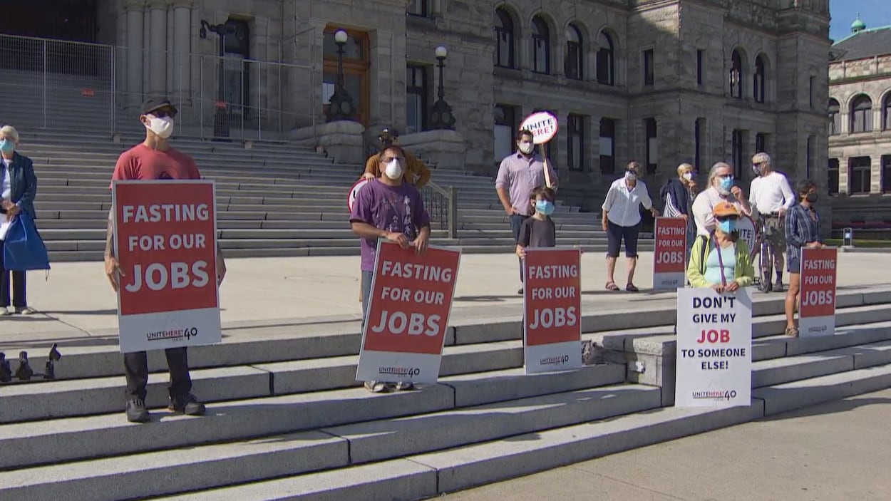 Des personnes brandissent des pancartes où il est écrit en anglais : je jeûne pour nos emplois.