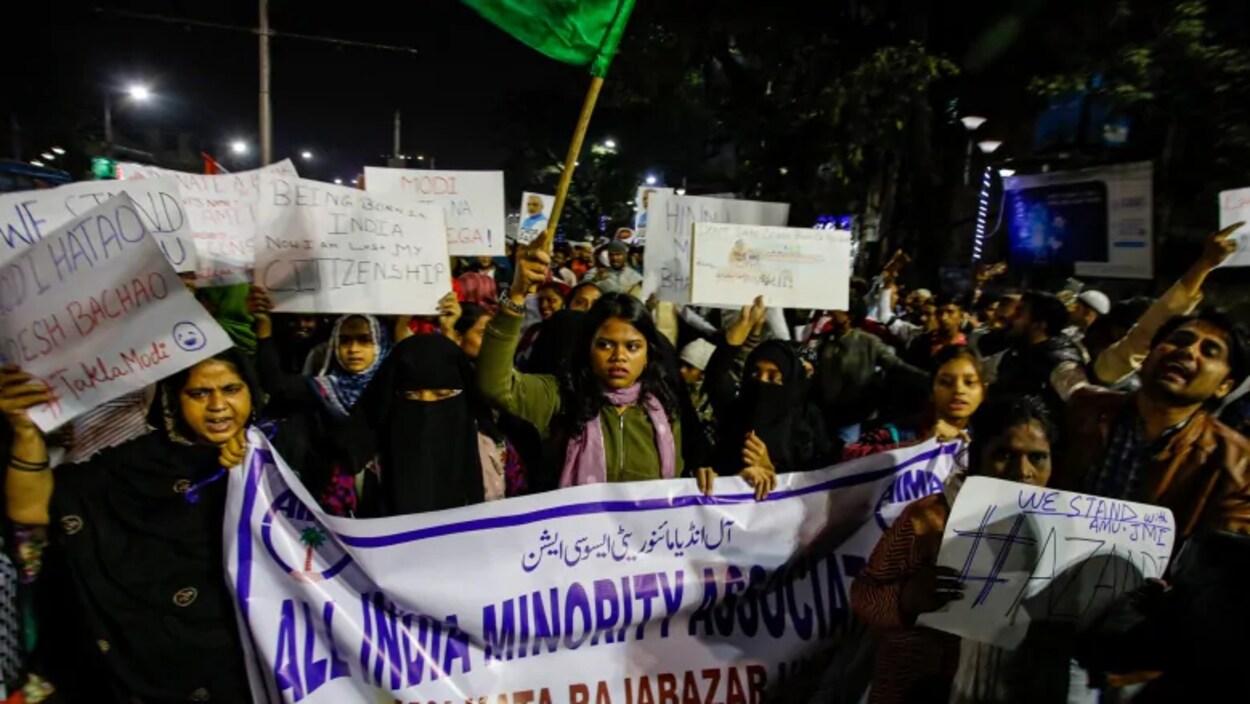 Des Indiens crient des slogans lors d'une manifestation, la nuit.