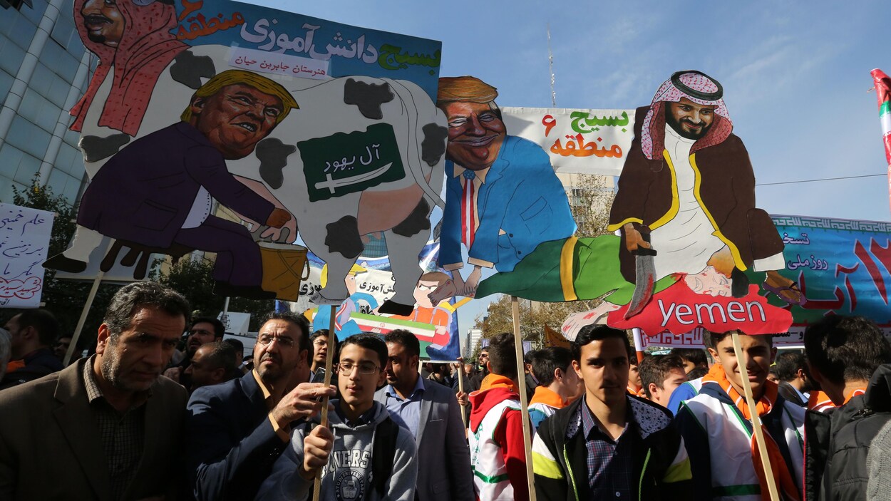 Des manifestants brandissant des caricatures montrant le président américain Donald Trump en train de traire le lait d'une vache frappé d'un drapeau saoudien sur le côté et portant la tête du roi Salmane d'Arabie saoudite.