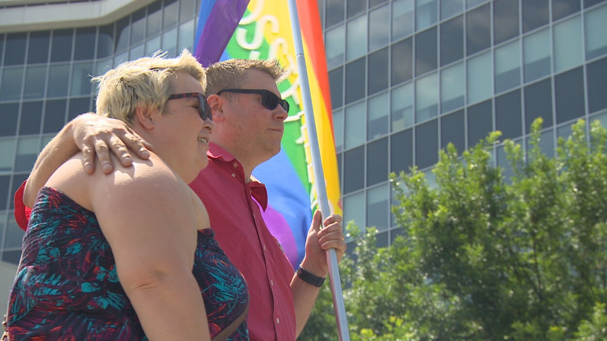 Deux personnes se tenant par l'épaule ayant un drapeau à la main.