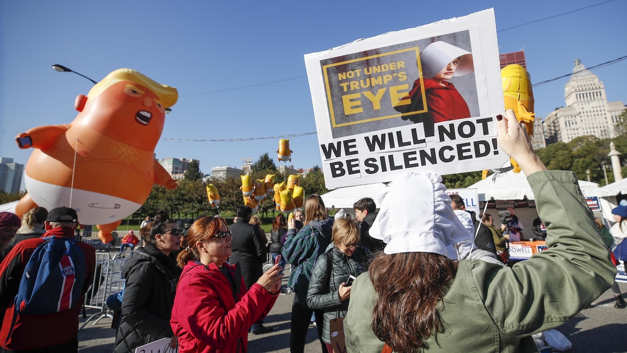 Un groupe de manifestants avec des pancartes et un ballon gonflable géant à l'effigie de Donald Trump marchent dans les rues de Chicago. Un groupe de manifestants avec des pancartes et un ballon gonflable géant à l'effigie de Donald Trump marchent dans les rues de Chicago.