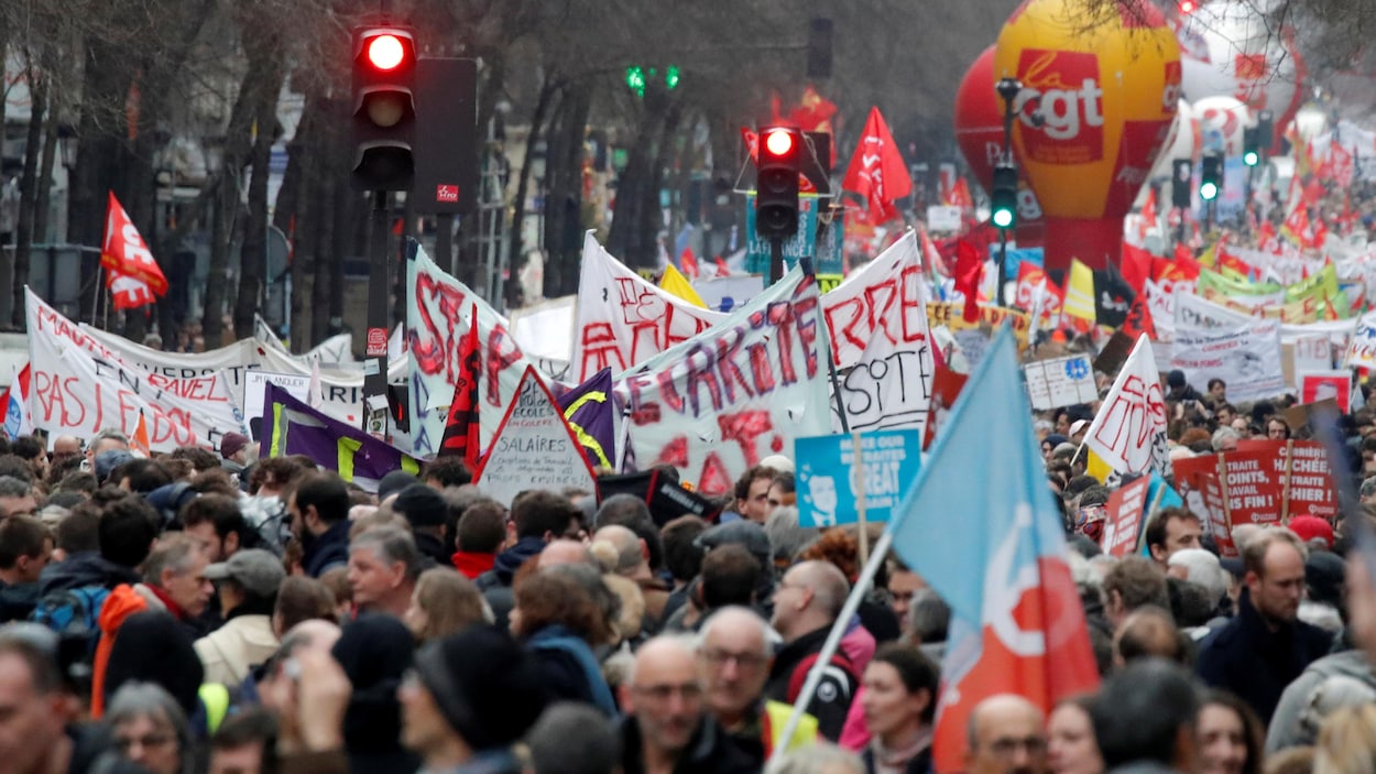 Des centaines de personnes marchent dans une rue de Paris. On voit de multiples banderoles.