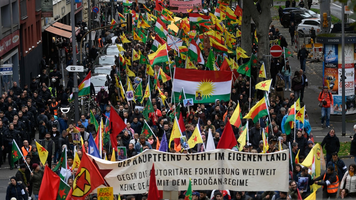 Une foule défile dans une rue de Cologne, en Allemagne, en brandissant des drapeaux et en tenant une banderole, le 19 octobre 2019.