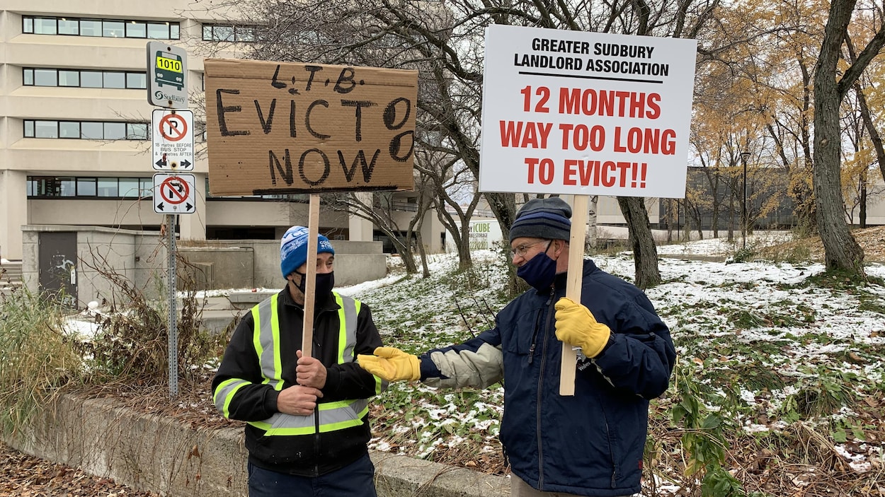 Deux manifestants tiennent des pancartes.